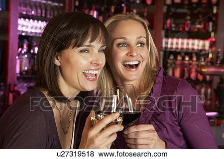 Stock Photo - Two Women Enjoying Drink Together In Bar. Fotosearch