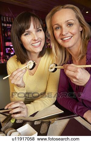 Stock Photo - Two Women Enjoying Sushi In Restaurant. Fotosearch