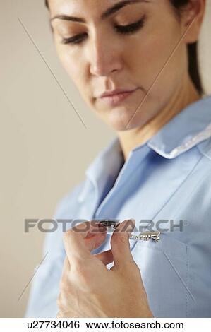 Stock Photograph - UK nurse looking at watch. Fotosearch