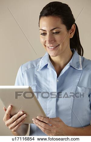 Picture - UK nurse using computer tablet. Fotosearch