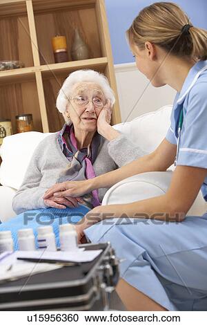 Stock Image - UK nurse visiting senior woman at home. Fotosearch
