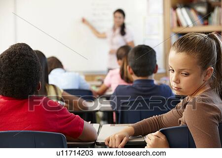 Stock Image - Unhappy schoolgirl in class. Fotosearch