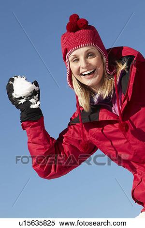 Stock Photography - Woman About To Throw Snowball Wearing Warm Clothes On Ski Holiday In Mountains. Fotosearch