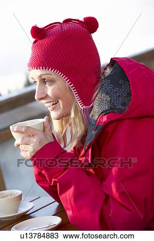 Stock Image - Woman Enjoying Hot Drink In CafÃ© At Ski Resort. Fotosearch