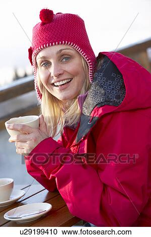 Stock Image - Woman Enjoying Hot Drink In CafÃ© At Ski Resort. Fotosearch