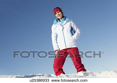 Stock Image - Woman Standing In Snow Wearing Warm Clothes On Ski Holiday In Mountains. Fotosearch
