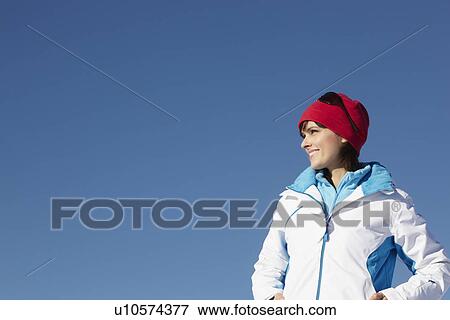 Stock Photo - Woman Standing In Snow Wearing Warm Clothes On Ski Holiday In Mountains. Fotosearch