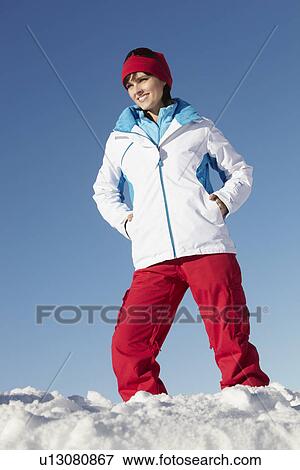 Stock Photo - Woman Standing In Snow Wearing Warm Clothes On Ski Holiday In Mountains. Fotosearch