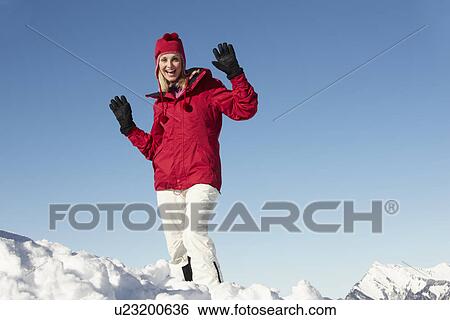 Stock Photograph - Woman Standing In Snow Wearing Warm Clothes On Ski Holiday In Mountains. Fotosearch