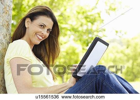 Stock Photograph - Woman using tablet outdoors. Fotosearch