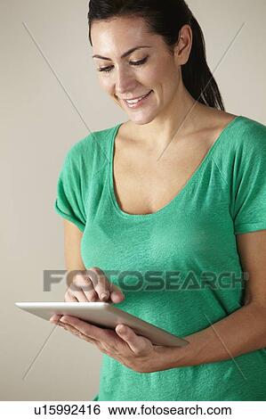 Stock Photograph - Woman using tablet studio shot. Fotosearch