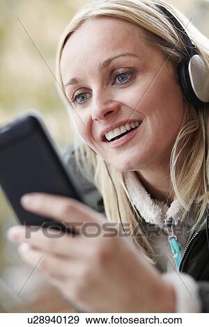Woman Wearing Headphones And Listening To Music On Smartphone Wearing Winter Clothes View Large Photo Image Stock Photo - Woman Wearing Headphones And Listening To Music On Smartphone Wearing Winter Clothes. Fotosearch
