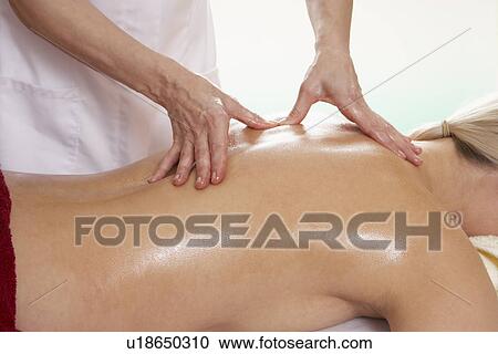 Stock Image - Woman with tattoo having back massage. Fotosearch