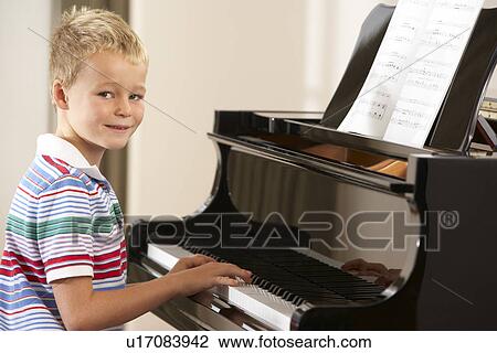 Stock Image - Young boy playing grand piano at home. Fotosearch