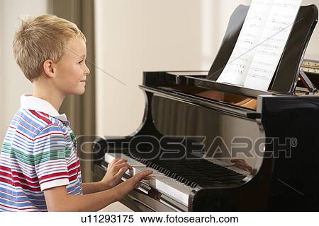 Stock Photography - Young boy playing grand piano at home. Fotosearch