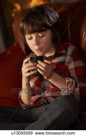 Young Boy Relaxing With Hot Drink By Cosy Log Fire View Large Photo Image Stock Photo - Young Boy Relaxing With Hot Drink By Cosy Log Fire. Fotosearch