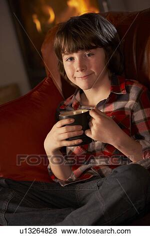 Young Boy Relaxing With Hot Drink By Cosy Log Fire View Large Photo Image Stock Photo - Young Boy Relaxing With Hot Drink By Cosy Log Fire. Fotosearch