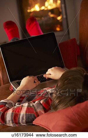 Picture - Young Boy Relaxing With Laptop By Cosy Log Fire. Fotosearch