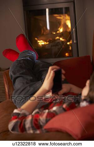 Young Boy Relaxing With MP3 Player By Cosy Log Fire View Large Photo Image Stock Photo - Young Boy Relaxing With MP3 Player By Cosy Log Fire. Fotosearch