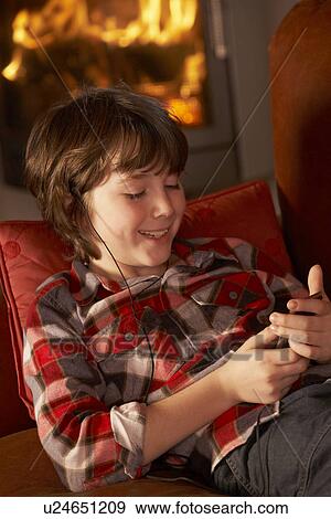 Stock Photo - Young Boy Relaxing With MP3 Player By Cosy Log Fire. Fotosearch