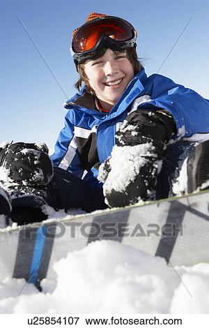 Stock Photo - Young Boy Sitting In Snow With Snowboard. Fotosearch