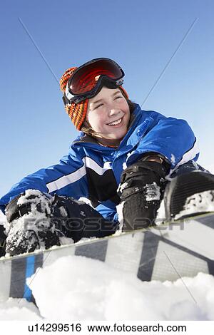 Stock Photograph - Young Boy Sitting In Snow With Snowboard. Fotosearch
