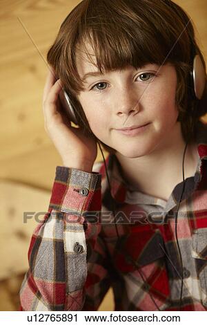 Stock Image - Young Boy Sitting On Wooden Seat Listening To MP3 Player. Fotosearch