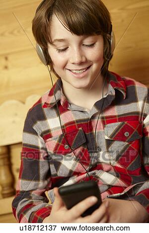 Stock Photo - Young Boy Sitting On Wooden Seat Listening To MP3 Player. Fotosearch
