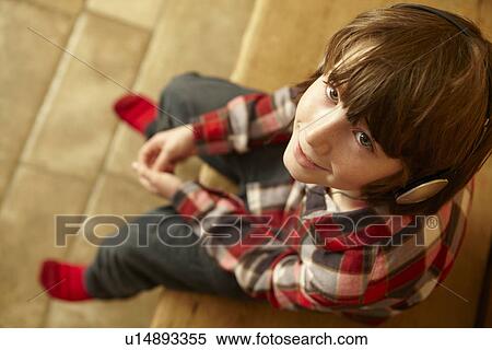 Stock Photography - Young Boy Sitting On Wooden Seat Listening To MP3 Player. Fotosearch