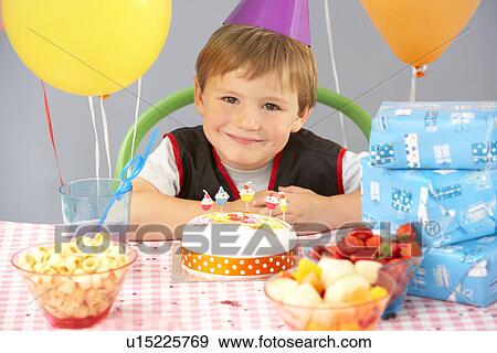 Stock Photo - Young boy with birthday cake and gifts at party. Fotosearch