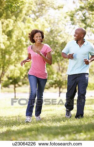 Young couple running in park View Large Photo Image Stock Photograph - Young couple running in park. Fotosearch