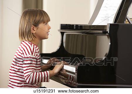 Stock Image - Young girl playing grand piano at home. Fotosearch