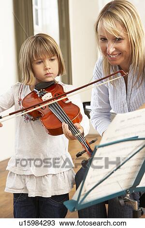 Stock Image - Young girl playing violin in music lesson. Fotosearch