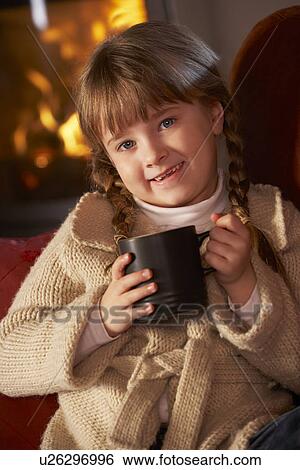 Stock Photograph - Young Girl Relaxing With Hot Drink By Cosy Log Fire. Fotosearch