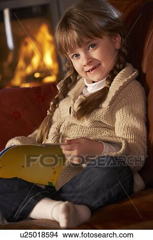 Young Girl Sitting On Sofa And Reading Book By Cosy Log Fire View Large Photo Image Picture - Young Girl Sitting On Sofa And Reading Book By Cosy Log Fire. Fotosearch