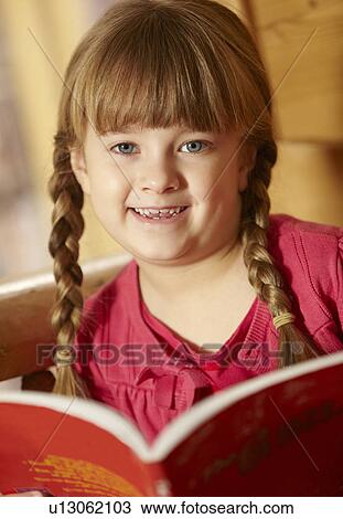 Stock Image - Young Girl Sitting On Wooden Seat Reading Book. Fotosearch