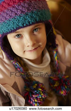 Stock Image - Young Girl Sitting On Wooden Seat Wearing Warm Outdoor Clothes. Fotosearch