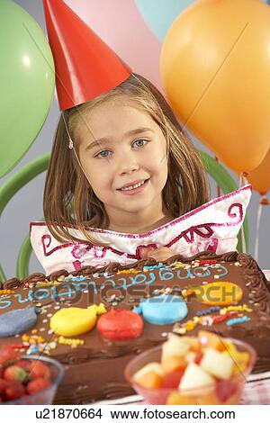 Picture - Young girl with birthday cake at party. Fotosearch