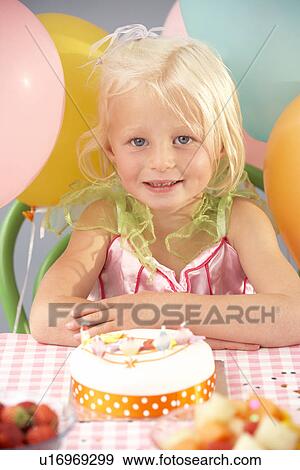 Stock Photo - Young girl with birthday cake at party. Fotosearch