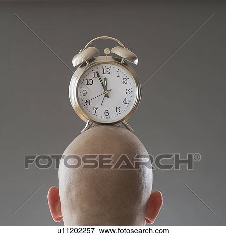 Stock Photo - Back view of man with alarm clock on shaved head. Fotosearch