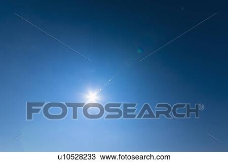 Stock Image - Blue sky lit with bright sunshine. Fotosearch