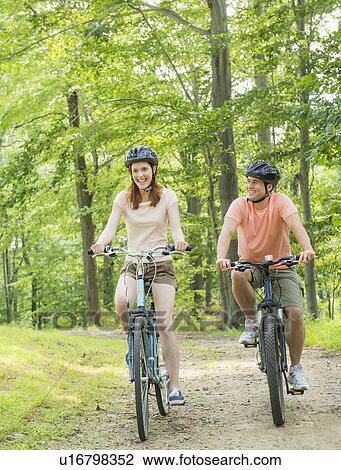 Couple cycling in forest View Large Photo Image Stock Image - Couple cycling in forest. Fotosearch
