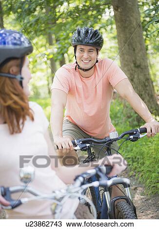 Stock Image - Couple cycling in forest. Fotosearch