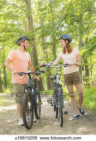 Couple cycling in forest View Large Photo Image Stock Photo - Couple cycling in forest. Fotosearch