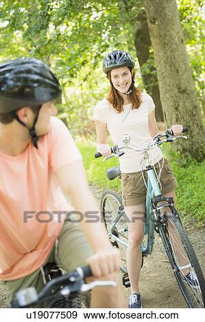 Couple cycling in forest View Large Photo Image Stock Photo - Couple cycling in forest. Fotosearch