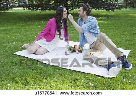 Stock Image - Couple having picnic in park. Fotosearch