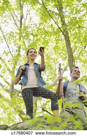 Stock Photo - Couple hiking with GPS in forest. Fotosearch