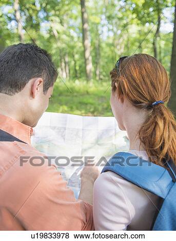 Stock Photo - Couple hiking with map in forest. Fotosearch