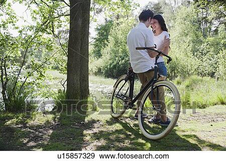 Couple kissing near bike View Large Photo Image Stock Photo - Couple kissing near bike. Fotosearch