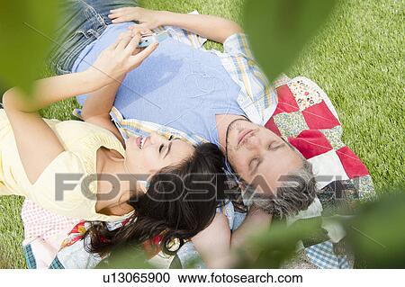 Couple lying together on grass View Large Photo Image Stock Image - Couple lying together on grass. Fotosearch